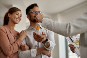 Home - closeup real estate agent giving couple keys their new home scaled
