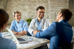Home - group healthcare workers greeting financial advisor meeting office focus is young doctor scaled