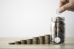 Home - hand die munze zum speichern des glases und des stapelns von munzen legt geldsparendes investitionsgewinn und dividendenkonzept scaled
