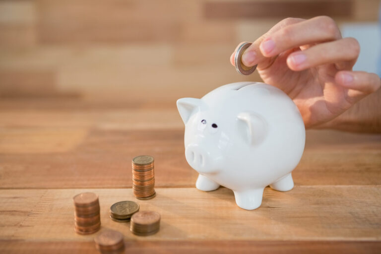 News - hand inserting coin piggy bank scaled