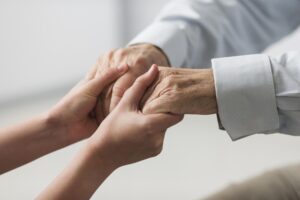 Home - nurse holding senior man s hands sympathy scaled