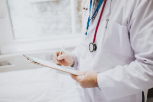 Home - physician noting down symptoms patient scaled