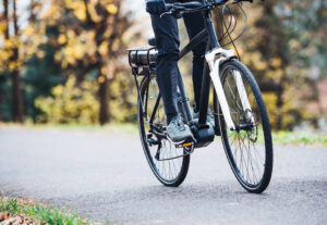 Home - unrecognizable man electrobike cycling outdoors road park scaled